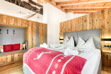Schlafzimmer in Chalet 1 mit Doppelbett und Tür zum Balkon