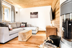 Wohnbereich in Chalet 3 mit Ecksofa und rundem Kaminofen