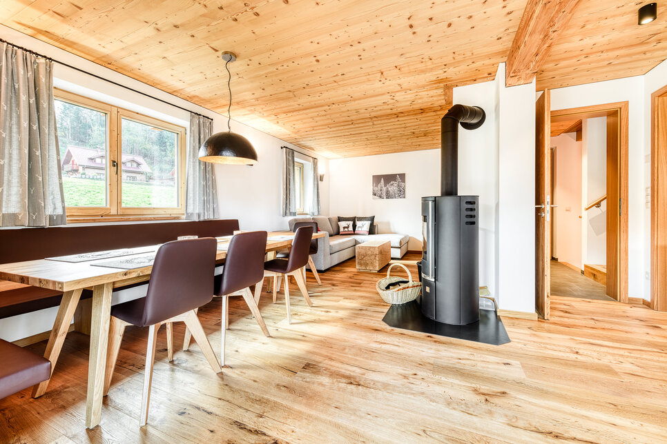 Ess- und Wohnbereich in Chalet 3 mit langem Tisch und Kaminofen