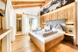 Schlafzimmer in Chalet 3 mit Doppelbett vor einer Wand aus Altholz