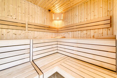 Sauna im Innenhof von Chalet 1, mit Bänken über Eck auf zwei Ebenen