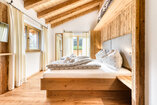 Schlafzimmer in Chalet 2 mit Doppelbett in einer Nische aus Altholz