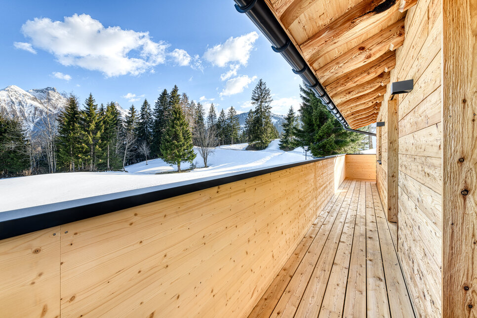 Der umlaufende Balkon von Chalet 1 mit Blick auf die verschneiten Berge